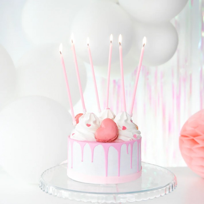 Zestaw ośmiu długich różowych świeczek urodzinowych na białym tle.